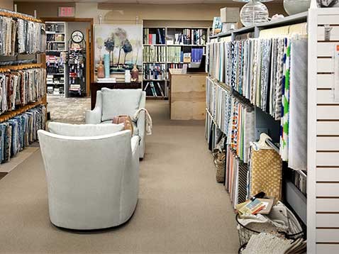 Store interior with a pair of chairs surrounded by fabric samples