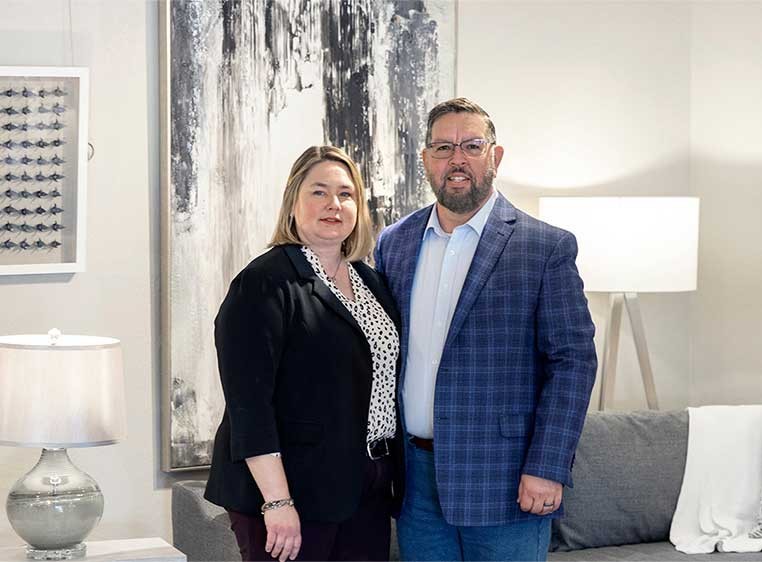 A smiling couple, standing in a well furnished room